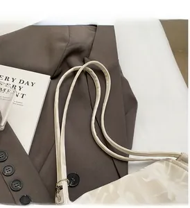 Close-up of white printed tote bag on brown blazer with reinforced handle detail