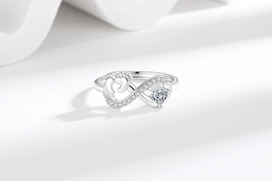 Macro detail of infinity ring featuring heart zircon, baby footprints, and pavé setting