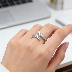 Verstellbarer silberner Feder-Flügel-Ring am Finger eines Models im modernen Büro