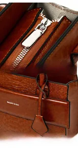 Detail of vintage brown crocodile texture tote bag with silver zipper and charm