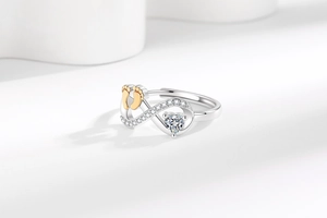 Detail of infinity ring with heart stone, golden footprint decor and micro-pavé setting
