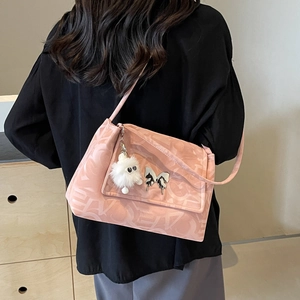 Detail of pink tote bag with letter texture, silver butterfly and white pompom charm