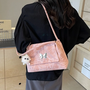 Detail of pink jacquard tote bag with silver butterfly charm and white plush monster keychain