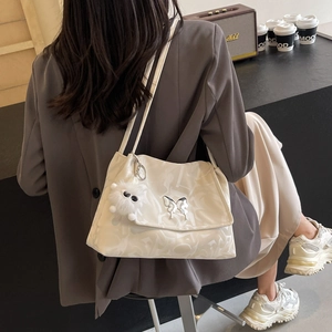 White PU tote bag with butterfly and plush charms worn by model in casual scene