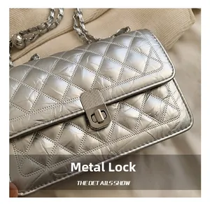 Close-up of metallic silver quilted bag with a textured metal twist lock and chain strap