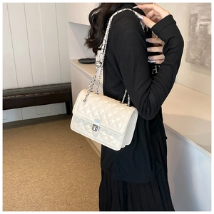 Detail of quilted leather texture and silver chain strap on cream white crossbody bag