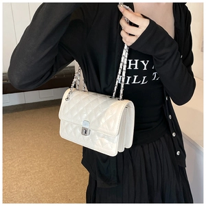 Detail view of white quilted chain bag showing the silver twist lock and side gusset
