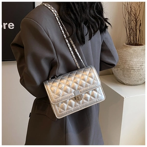Detail of silver quilted chain bag with metallic finish and elegant twist lock closure