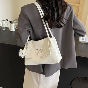 Detail of silver tote bag featuring a metal butterfly clasp and plush charm accessory