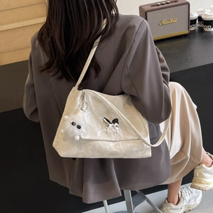 Detail of white jacquard tote bag with silver butterfly buckle and plush pendant charm