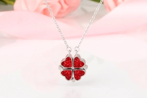 Détail du pendentif trèfle rouge avec pétales de cœur scintillants sur des roses
