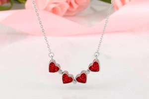 Détail du collier avec pendentifs cœurs rouges sertis de cristaux et chaîne argentée