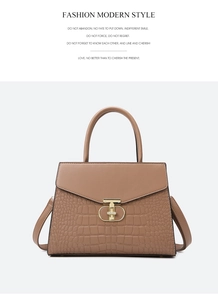 Detail of tan handbag with crocodile texture, gold T-buckle and stitching details