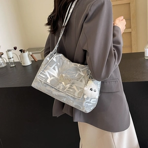 Silver tote bag featuring a metallic butterfly clasp and plush monster charm detail