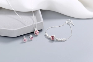 Detailed set of pink crystal necklace, bracelet, and earrings on silk background