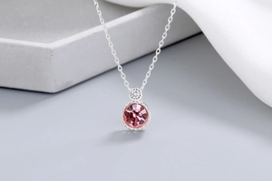 Close-up of pink crystal pendant necklace with sparkling stone on grey stone display