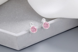 Detailed macro view of pink gemstone stud earrings on a textured stone display stand