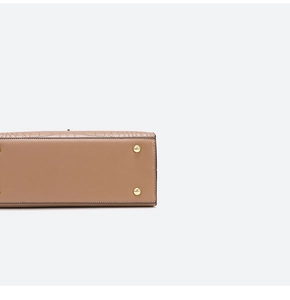 Close-up of golden protective bottom studs and crocodile texture on khaki handbag