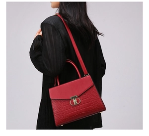 Detail of red croc-embossed handbag with gold metal lock and leather shoulder strap