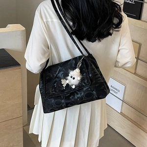 Detail of black tote bag with embossed texture and a white plush monster charm
