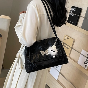 Detail of black nylon shoulder bag with silver butterfly charm and plush doll pendant