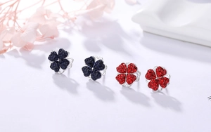 Détail de boucles d'oreilles trèfle rotatives avec cristaux bleus et rouges sertis