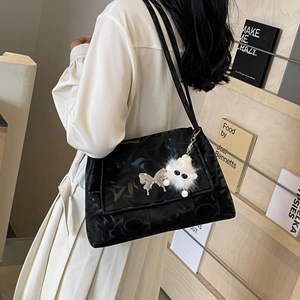 Detail of black printed tote bag with metal butterfly and plush doll charm accessories