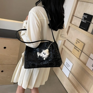 Detail of black nylon shoulder bag with abstract texture and white plush pendant accessory