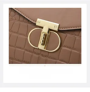 Detail of a brown crocodile pattern leather handbag with a sleek gold T-bar metal lock