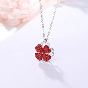 Détail macro du pendentif trèfle rotatif avec cristaux rouges et chaîne en argent