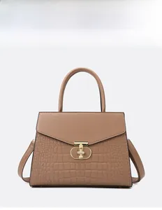 Detailed view of crocodile pattern texture and gold T-shaped lock on a brown tote bag