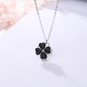 Vue macro d'un pendentif trèfle rotatif avec cristaux noirs sur chaîne argent