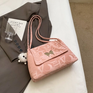 Detail of light pink shoulder bag with gold butterfly buckle and plush charm on the side