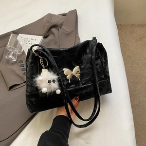 Detail of black tote bag featuring silver butterfly buckle and fuzzy monster charm