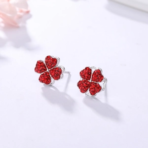 Détail macro de boucles d'oreilles trèfle en argent avec cristaux rouges pavés