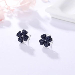 Gros plan sur les boucles d'oreilles trèfle avec zircons bleu foncé sertis pavé