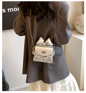 Detail of silver bow clutch showing metallic texture, 3D bow, and silver chain strap