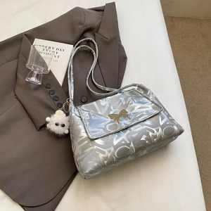 Close-up of silver tote bag featuring butterfly clasp and white plush ball charm