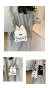 Close-up of a white patent leather mini bag with a bow knot and silver metal chains