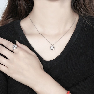 Detail view of silver hollow floral necklace and matching ring on model in black knitwear