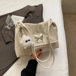 Detail of cream PU leather tote bag with silver butterfly and plush monster charm