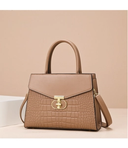 Detail of stone pattern texture and gold T-shaped clasp on a khaki leather handbag