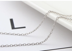 Macro detail of silver necklace chain link texture on white ceramic plate