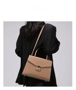 Detail view of khaki faux leather shoulder bag with crocodile texture and gold metal clasp