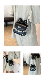 Detail of black mini box bag featuring glossy wrinkled leather and silver bow chain