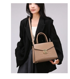 Detail of khaki handbag with crocodile texture and golden metal buckle decoration