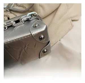 Macro detail of silver mini box bag featuring textured metallic finish and polished rivets