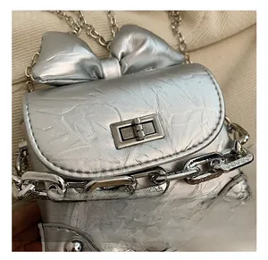 Close-up of a silver metallic mini bag with a leather bow and shiny turn-lock clasp