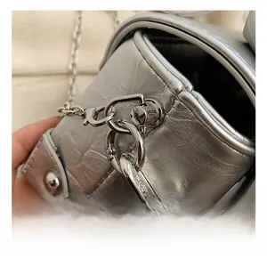 Detail of the silver chain strap hook and metallic crinkled leather on a mini box bag