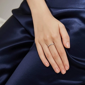 Close-up of minimalist silver fidget ring on finger with dark blue satin background